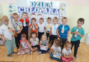 Grupa starszaków pozuje do zdjęcia. Chłopcy ubrani w kolorowe krawaty, dziewczynki trzymają własnoręcznie wykonane torebki.