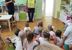 Panie policjantki demonstrują dzieciom kamizelkę odblaskową.