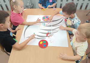 Dzieci wykonują pracę plastyczną z wykorzystaniem kółek origami