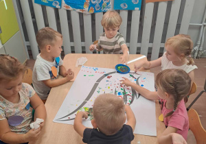 Dzieci wykonują przy stolikach pracę plastyczną