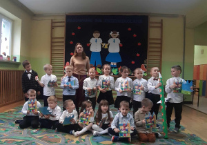 Zdjęcie grupowe dzieci 5-6 letnich z wychowawcą. W tle dekoracja.