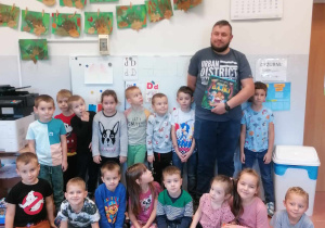 Zdjęcie grupowe przedszkolaków i taty dziecka z książką