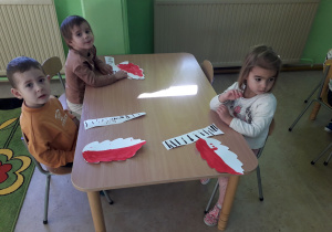 Przedszkolaki przygotowują elementy patriotycznej dekoracji.