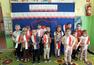 Przedszkolaki prezentują wykonane drzewka, które ozdobią patriotyczną dekorację.