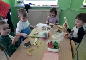 Dzieci przy stolikach wykonują "misiowe kanapki".