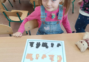 Siedząca dziewczynka w czasie wykonywania karty pracy z misiami