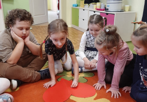 Dziewczynka przebija papierowe serce pinezką, kolejne ujęcie.