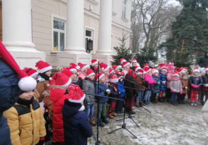 Dzieci stoją w półkolu i śpiewają kolędę