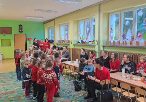 Dzieci stoją i śpiewają przed rodzicami kolędy