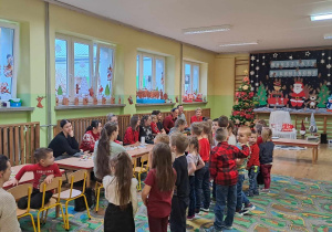 Dzieci stoją i śpiewają przed rodzicami kolędy