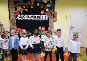 Dzieci ustawione w rzędzie recytują wiersze.