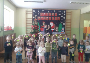 Przedszkolaki stoją w grupie z panią policjantką z odblaskami