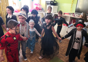 Przedszkolaki trzymją się za ręce i uczestniczą w zabawie muzyczno-ruchowej.