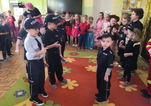 Przedszkolaki przebrane za policjantów prezentują swoje stroje.