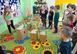 Dzieci przestawiają sylwety reniferów według instrukcji nauczycielki.