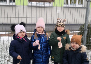Dzieci trzymają słoninkę dla ptaszków.