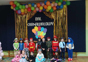 Dzieci z grupy starszaków pozują do zdjęcia grupowym. W tle dekorajac.