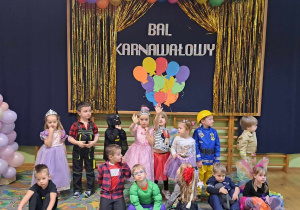 Dzieci z grupy młodszej pozują do zdjęcia grupowego. W tle dekoracja.