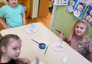Starszaki siedzą przy stoliku i wykonują pracę plastyczno-techniczną.