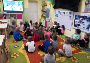 Przedszkolaki oglądają film edukacyjny o bezpiecznych zachowaniach podczas zabaw na śniegu.