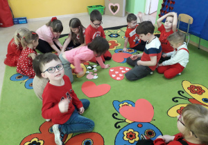 Dzieci na dywanie grają w "serduszkowe kółko i krzyżyk".