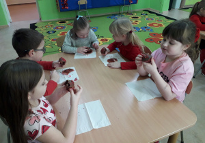 Dzieci przy stolikach zajadają się walentynkowymi muffinkami.
