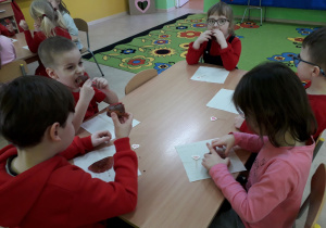Dzieci przy stolikach zajadają się walentynkowymi muffinkami.