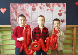 Dzieci z napisem love na tle dekoracji walentynkowej