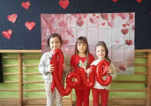 Dziewczynki z balonowym napisem love na tle dekoracji walentynkowej