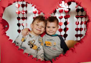 Chłopcy pozują do zdjęcia w serduszkowej fotobudce.