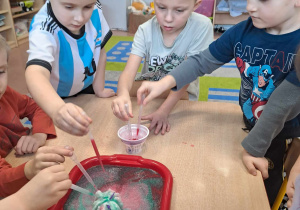 Dzieci przy stoliku z pipetami podczas eksperymentu