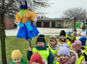 Dzieci ustawione w parach na placu przedszkolnym. Trzymają Marzannę.