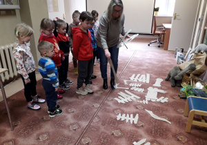 Dzieci układają szkielet dinozaura z wielu elementów.