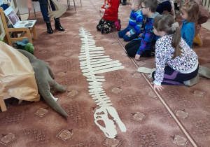 Dzieci kończą układanie szkieletu dinozaura.