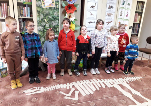 Dzieci pozują na tle szkieletu dinozaura.