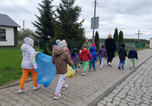 Dzieci porządkują teren wokół przedszkola.