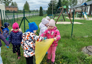 Dzieci porządkują teren wokół przedszkola.