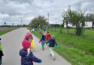 Dzieci porządkują teren wokół przedszkola.