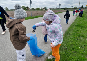 Dzieci porządkują teren wokół przedszkola.