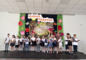 Absolwenci pozują do zdjęcia z dyplomami ukończenia przedszkola.
