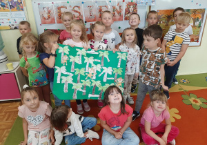 Dzieci pozują do fotografii prezentując wykonany przez siebie plakat przedstawiający palmowy gaj i małpkę Iwonę.