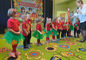 Pani dyrektor pokazuje dzieciom dużą kredkę do pasowania.