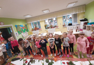 Dzieci stoją przed planszą dydaktyczną, na której ułożyły w odpowiedni sposób warzywa, zaznaczając ich część podziemną i nadziemną.