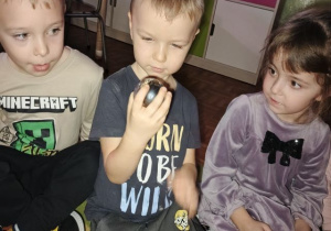 Przedszkolaki siedzą na dywanie i uczestniczą we wróżbie z magiczną kulą.