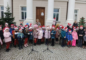 Dzieci stoją przed Pałacem w Starym Gostkowie i śpiewają świąteczne piosenki.