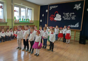 Dzieci recytują wiersz ustawione w rzędach.