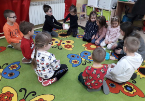 Dzieci na dywanie oglądają produkty potrzebne do produkcji mydełek.
