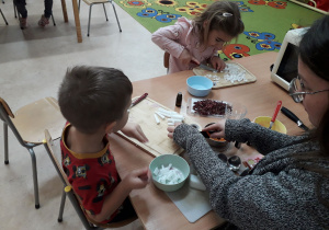 Dzieci przy stoliku tworzą swoje mydełka.