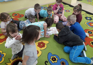Dzieci na dywanie oglądają mapę Krainy Biedronki Piątki.