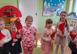Dziewczynki trzymają kwiatki i pozują do zdjęcia.
